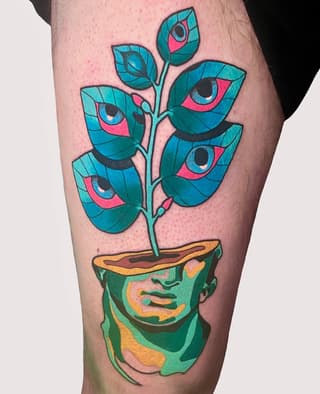 Colorful leg tattoo featuring a potted head with a plant growing from it, adorned with teal leaves and pink eyes, rendered in vibrant blues, greens, and yellows.