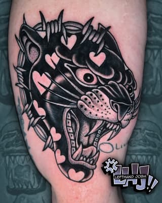 Decorative fish head with spikes, hearts, and detailed fins in black ink with pink skin tones on the thigh.