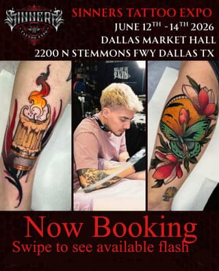 Tattoo artist with platinum blonde hair working on client designs featuring a flaming chalice, butterfly with red flowers, and colorful ink work displayed on arms.