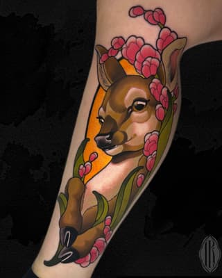 Deer head portrait surrounded by pink flowering branches on the forearm, rendered in brown, pink, orange, and green colors.