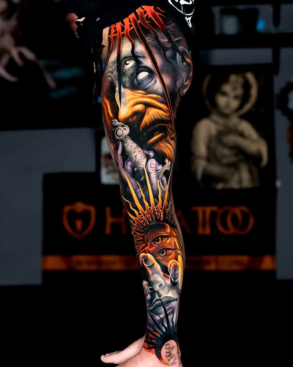 Full-leg sleeve tattoo featuring multiple portrait faces with orange, yellow, and purple tones, displayed on a standing leg against a dark studio background.