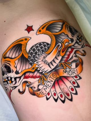 Colorful skull with orange bat wings, red mouth, black scales, and "MEMENTO MORI" text on the upper arm.