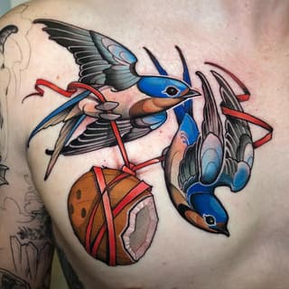 Colorful chest tattoo featuring two blue birds with red tail feathers perched on an orange spherical object with red ribbons.