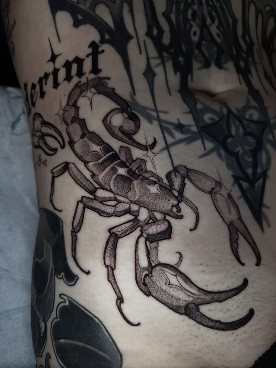 Detailed scorpion tattoo with dotted shading on the upper arm, rendered in black ink with fine linework and dimensional body segments.