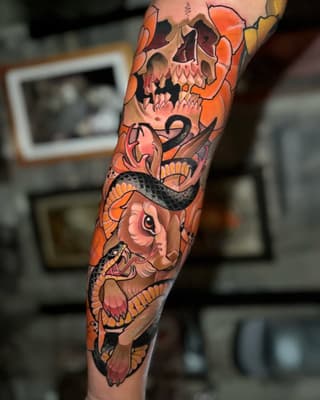 Full leg sleeve tattoo featuring a skull, snake, and orange flowers with detailed shading and bold black outlines in warm tones.