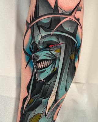 Skull with teal and black coloring, red eyes, and gold accents wrapped around the upper leg and thigh area.