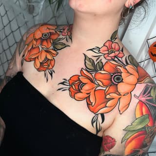 Colorful floral chest and shoulder tattoos featuring orange and red flowers with green leaves and black outlines on pale skin.