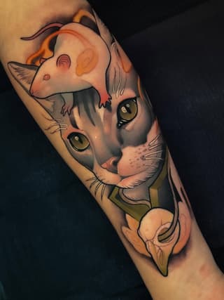 Two stacked cat faces with golden eyes and orange/peach coloring on the forearm, featuring detailed whiskers and shading in black, orange, and cream tones.