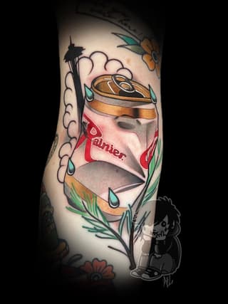 Colorful tattoo on an arm featuring a stylized face with a gold crown, red text reading "Panier," surrounded by flowers, teardrops, and a Space Needle silhouette.