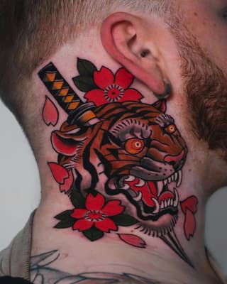 Colorful fish head tattoo with red flowers and black leaves on a person's neck, featuring orange and black striped details.