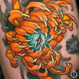 Vibrant orange flower with turquoise center and black stamen details surrounded by green leaves on upper arm or shoulder.