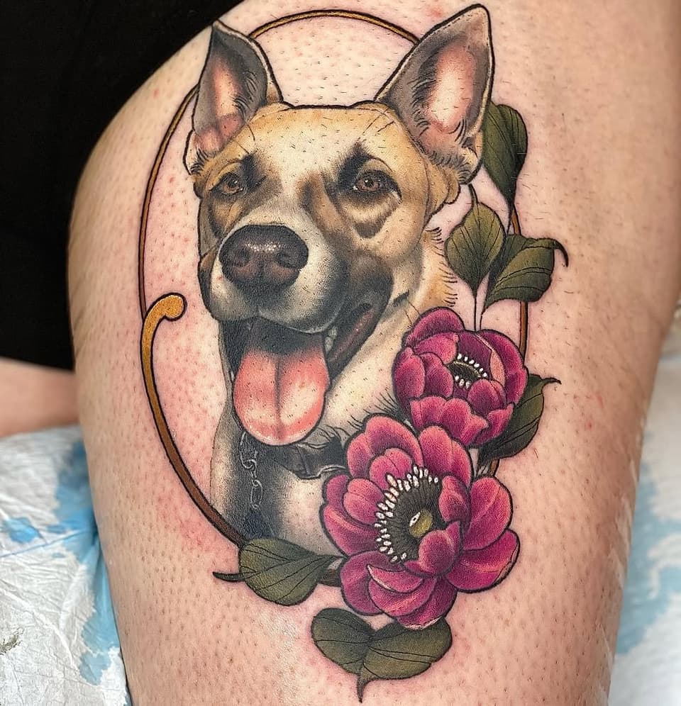 Dog portrait with pink peonies and decorative frame outline on thigh, featuring tan and black coloring with green foliage.