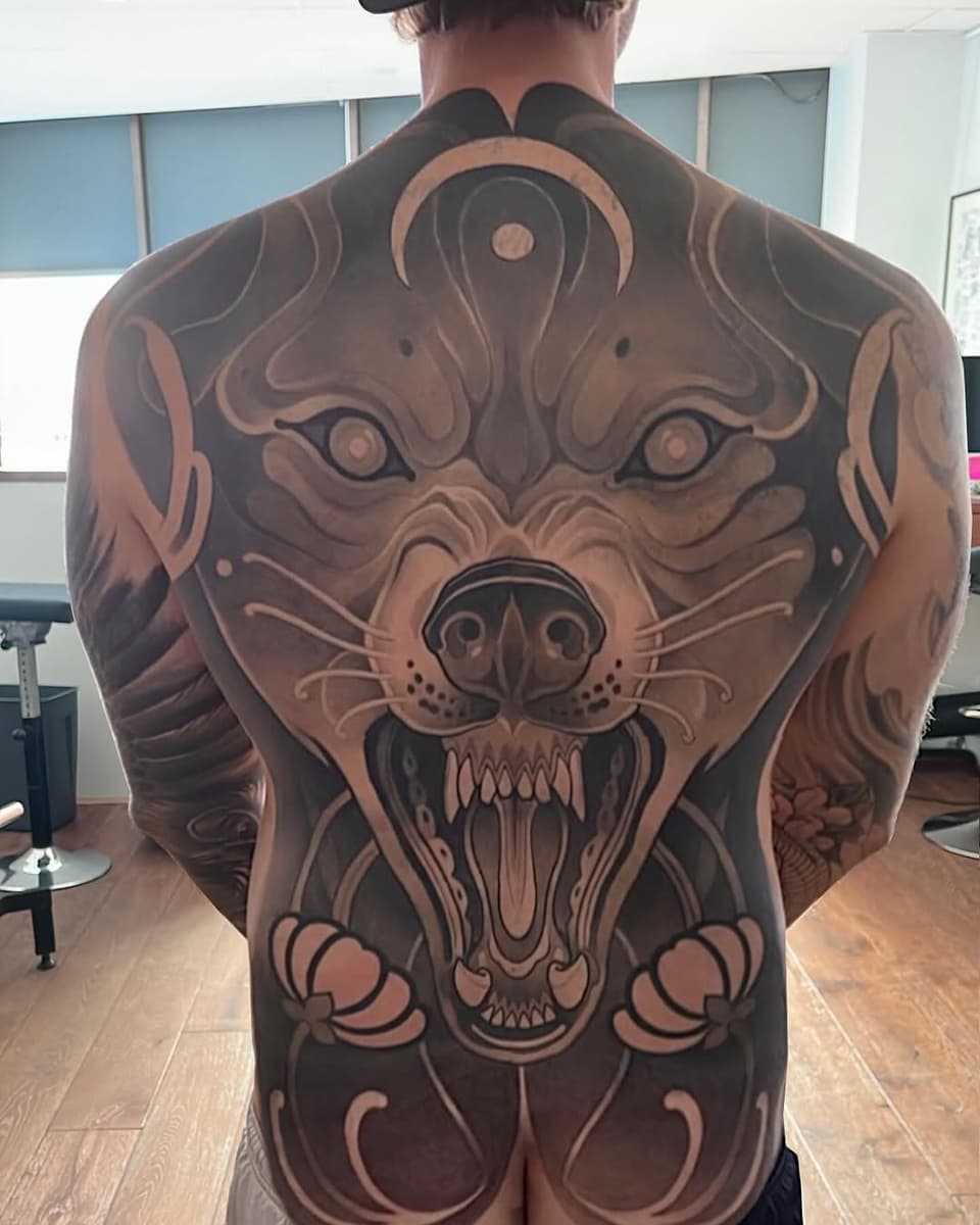 Large back tattoo featuring a snarling bear head with open mouth and bared teeth in brown and black ink.