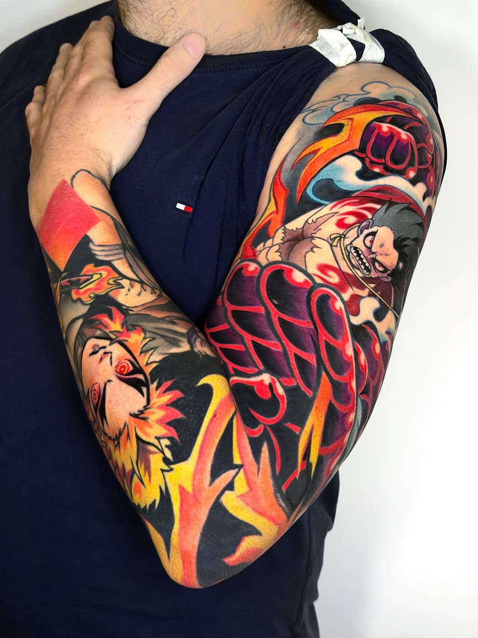 Colorful full-sleeve tattoo featuring a lion's head, human face, anatomical heart, and decorative elements in red, orange, yellow, and black ink on the arm.