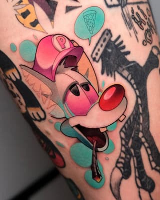 Colorful tattoo on leg featuring a cartoon character wearing a pink cap with an open mouth, surrounded by turquoise shapes and a speech bubble containing pizza.