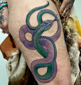 Colorful serpent tattoo on thigh featuring intertwined snakes with green scales and purple fins in shades of blue, green, and purple.