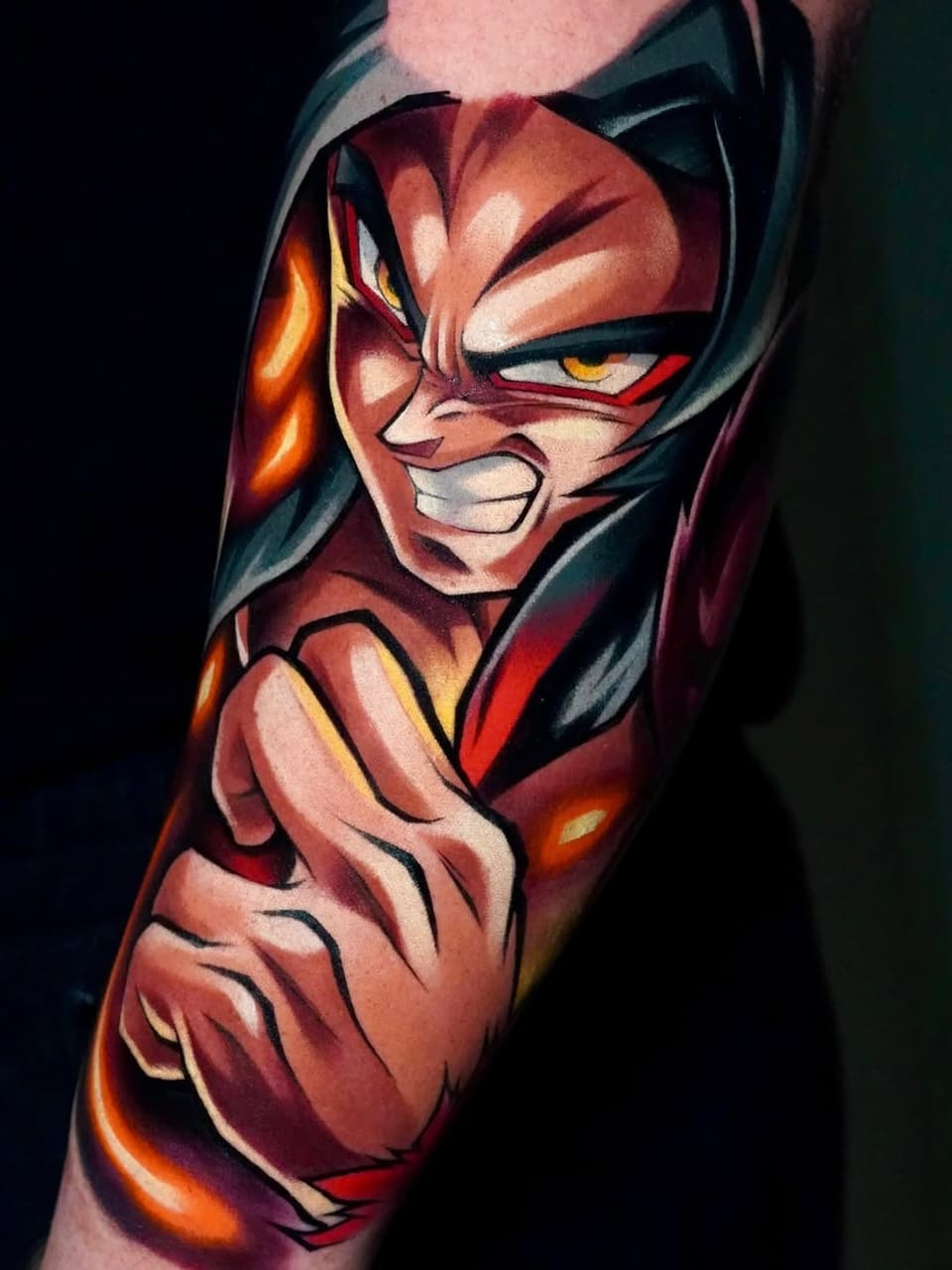 Colorful superhero character tattoo on the upper arm featuring red, orange, and yellow tones with dynamic facial expression and muscular shoulders.
