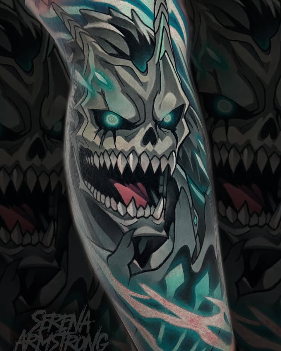 Skull tattoo with glowing teal eyes, sharp teeth, and geometric teal and gray patterns on the forearm, created by Serena Armstrong.