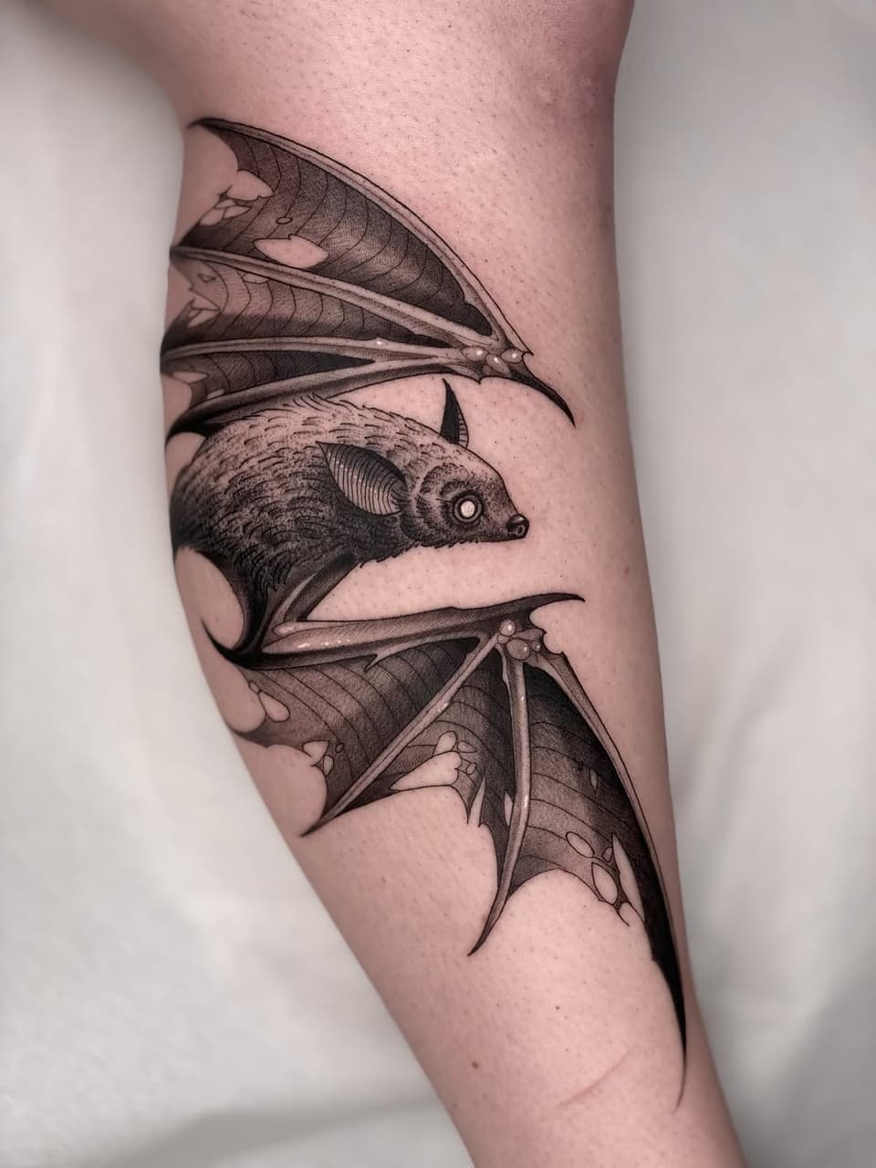 Three detailed bats with membranous wings and facial features rendered in black ink on the inner forearm.
