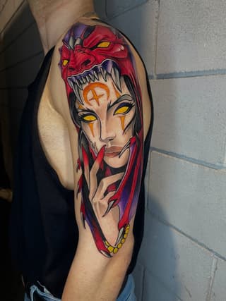 Colorful arm tattoo featuring a split-faced demonic figure with yellow eyes, red skin, sharp teeth, and flowing hair in red and purple tones.