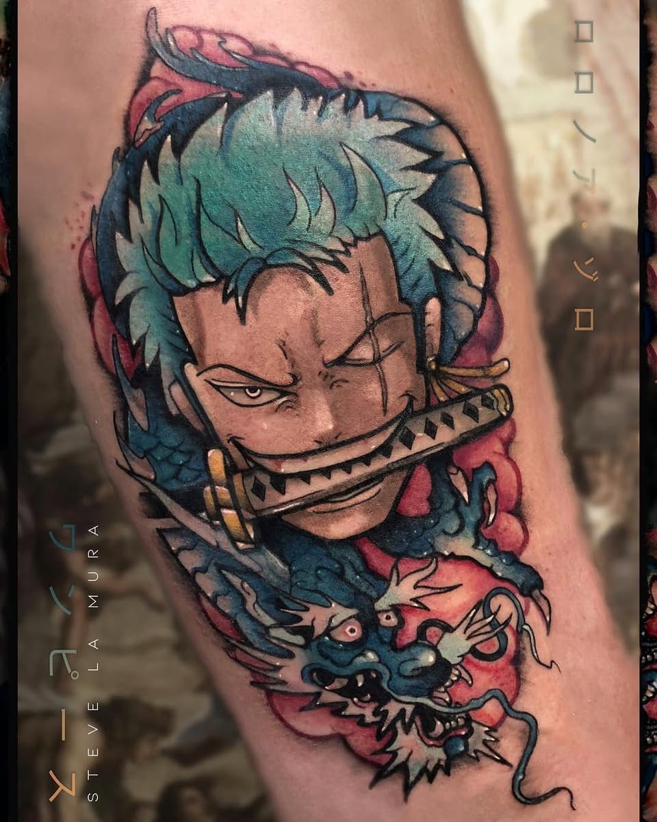 Colorful tattoo on upper arm featuring a character with teal hair and closed eyes, a decorative mouth piece, and a demon creature below in pink and blue tones.