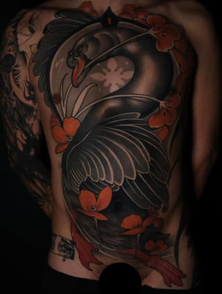 Large chest and shoulder tattoo featuring black birds with spread wings surrounded by red and orange flowers on tan skin.