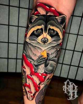 Colorful raccoon tattoo on the calf holding cheese, surrounded by red mushrooms and yellow flowers, with gold eyes and detailed shading.