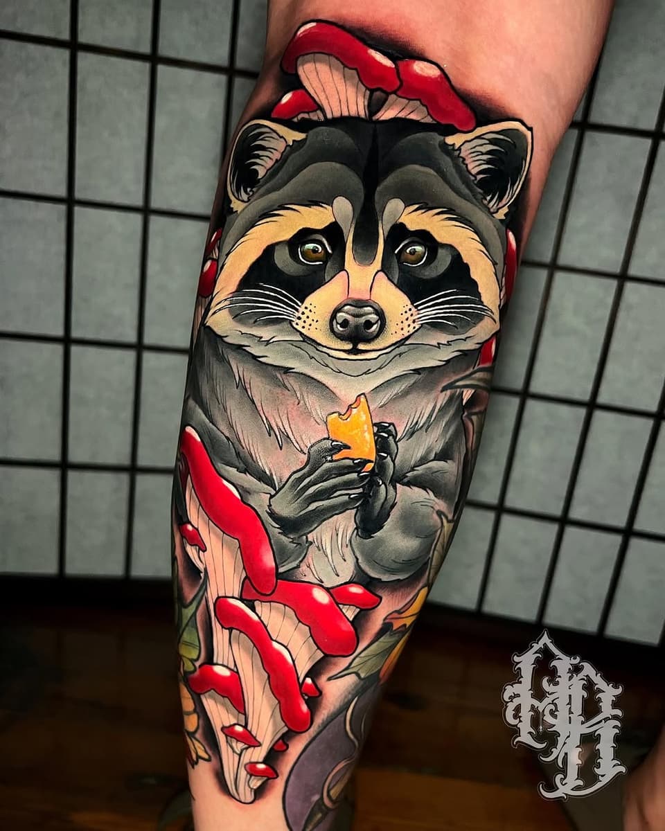 Colorful raccoon tattoo on the calf holding cheese, surrounded by red mushrooms and yellow flowers, with gold eyes and detailed shading.