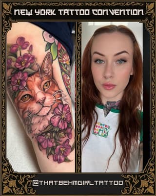 Colorful cat head surrounded by purple flowers with butterfly and green leaves on upper arm, shown on person with reddish-brown hair.