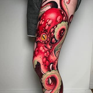 Full-leg tattoo sleeve featuring vibrant red octopus with yellow eye, green tentacle details, and pink circular patterns from thigh to ankle.