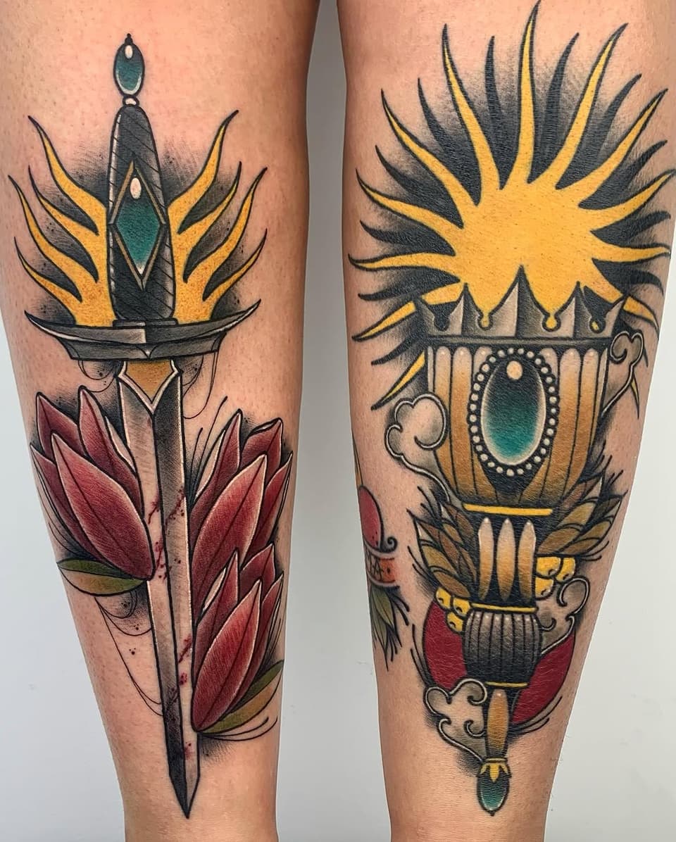 Two leg tattoos featuring ornate torches with radiating flames, red flowers, and jeweled vessels in yellow, red, teal, and black colors.