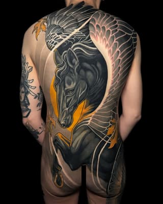 Large-scale winged horse tattoo spanning the back in black, grey, and gold with feathered wings extending across the shoulders and sides.