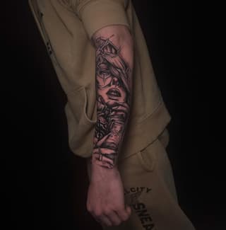 Detailed portrait tattoo on the forearm featuring a woman's face with ornate headpiece and additional facial imagery, rendered in black and red ink.