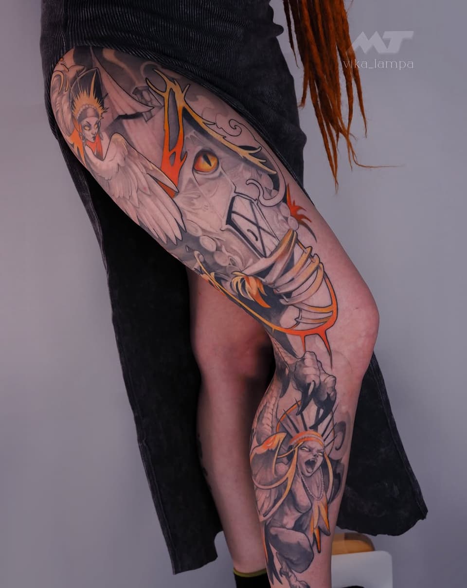 Colorful leg tattoo featuring a skull with wings, angelic figures, and ornamental details in orange, gold, and grey tones on the thigh and calf.