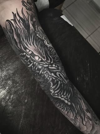 Detailed wing and feather tattoo covering the forearm with intricate linework and shading in black ink on pale skin.