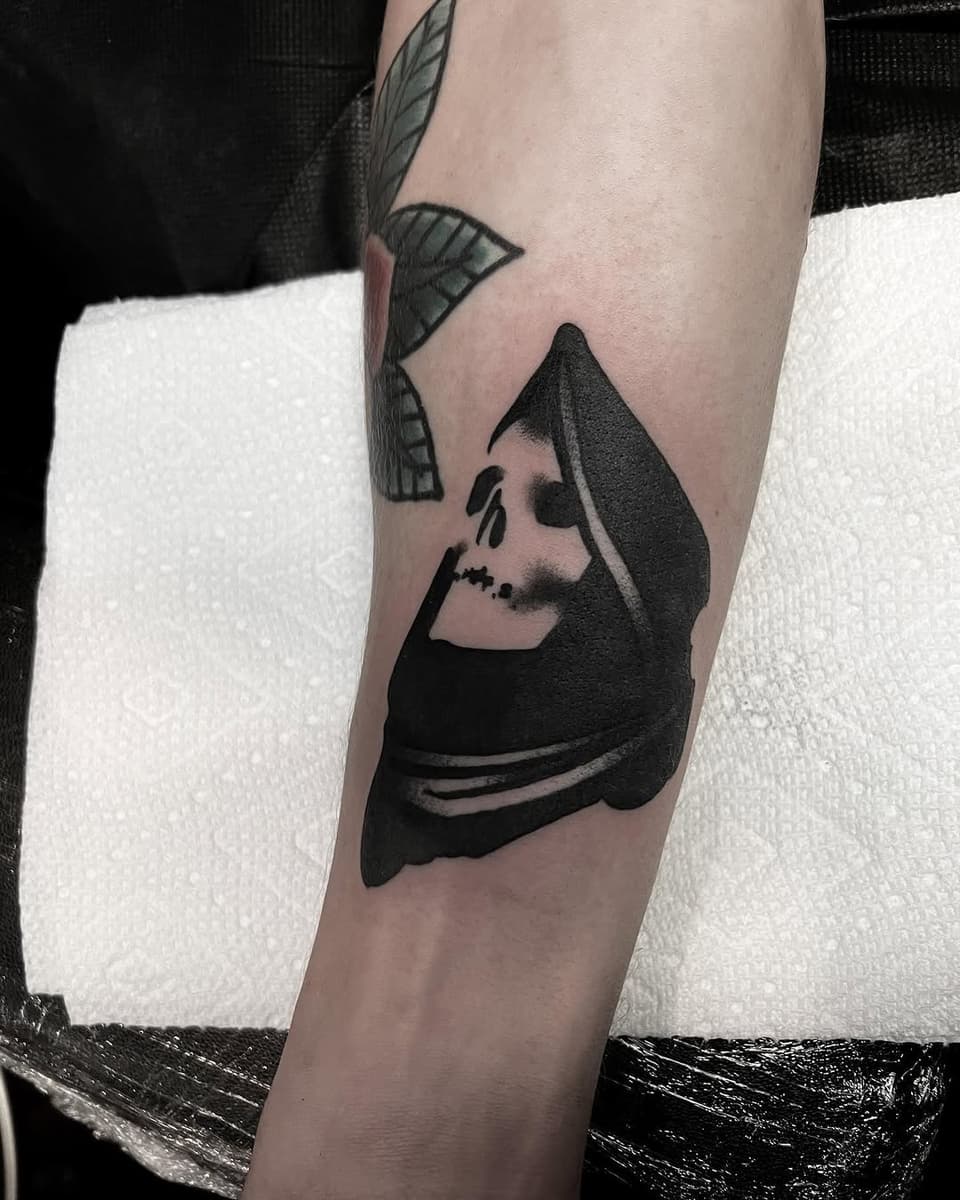 Hooded skeletal figure with leaf motifs on upper arm, rendered in black and gray ink on pale skin.