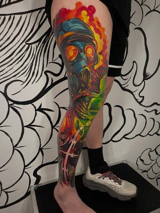 Full-leg sleeve tattoo featuring a skull with glowing eyes and gas mask, surrounded by vibrant red, orange, yellow, and green flames and abstract elements.