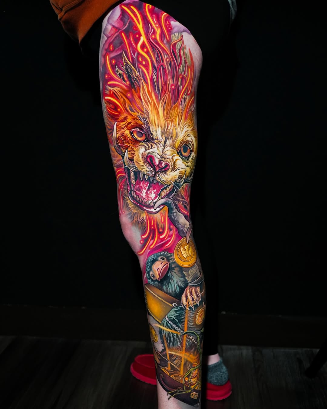 Full leg sleeve featuring a flaming lion head with fierce expression, smaller monkey character below, gold coins and ornamental details throughout.