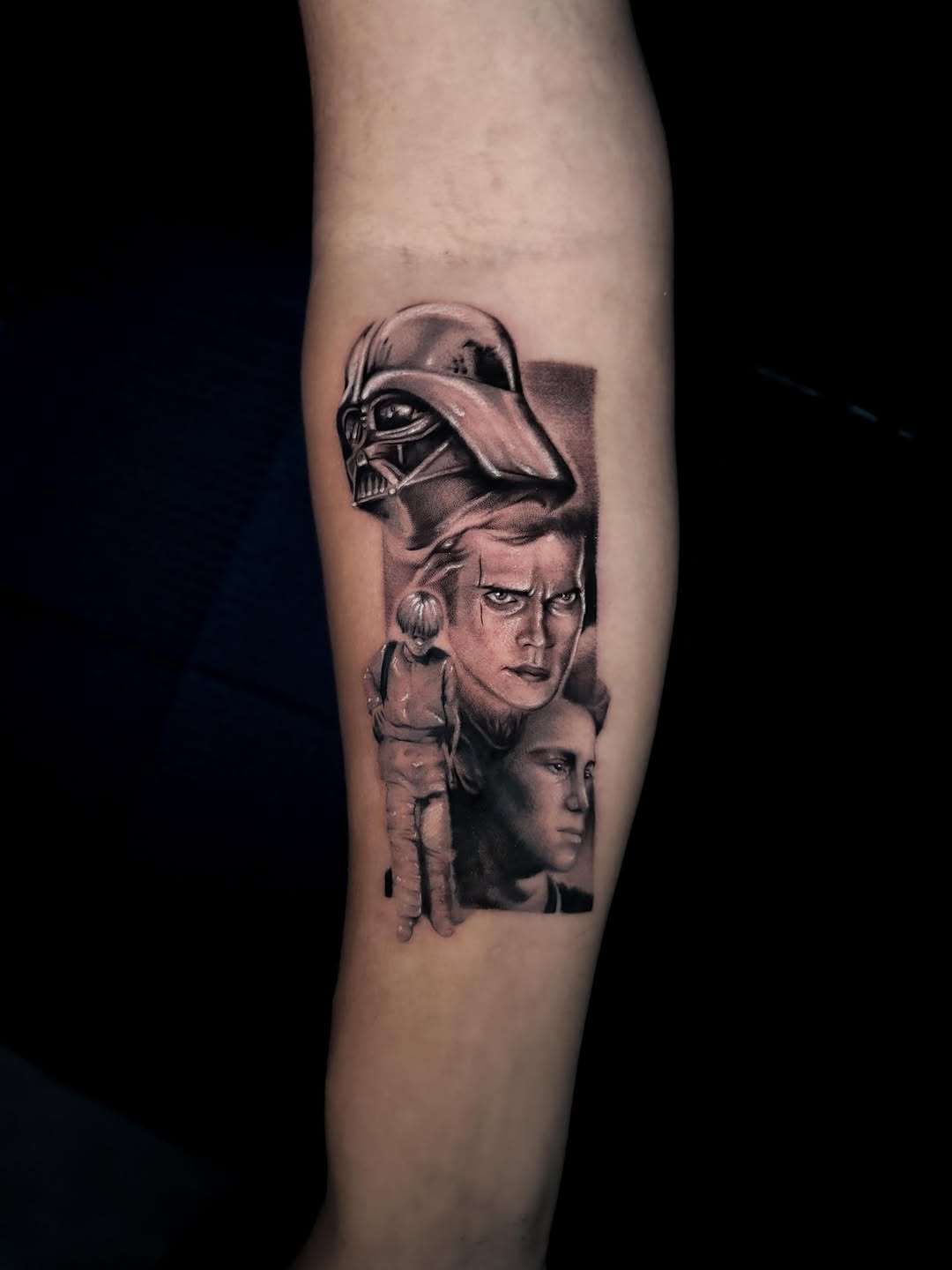 Three stacked portrait heads in black and grey on forearm: Darth Vader helmet above two male faces with detailed shading.