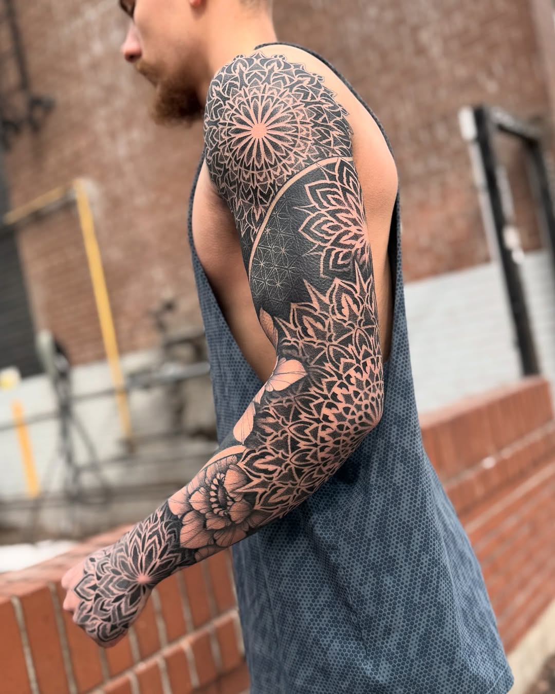 Full sleeve mandala and geometric pattern tattoo in black ink with intricate dotwork and symmetrical design covering the entire arm.