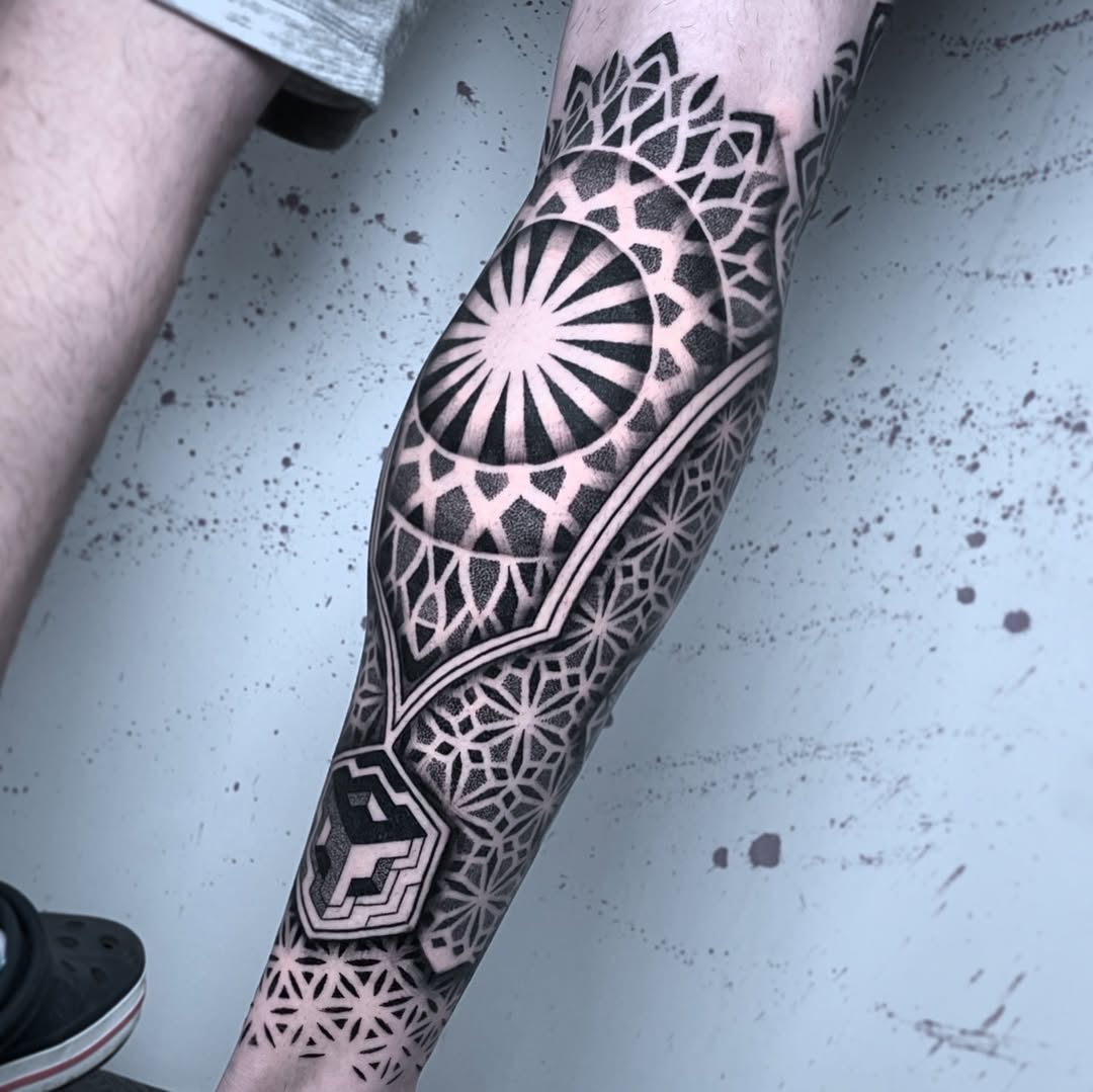 Geometric mandala and sunburst pattern with intricate dotwork and symmetrical ornamental linework covering the forearm.