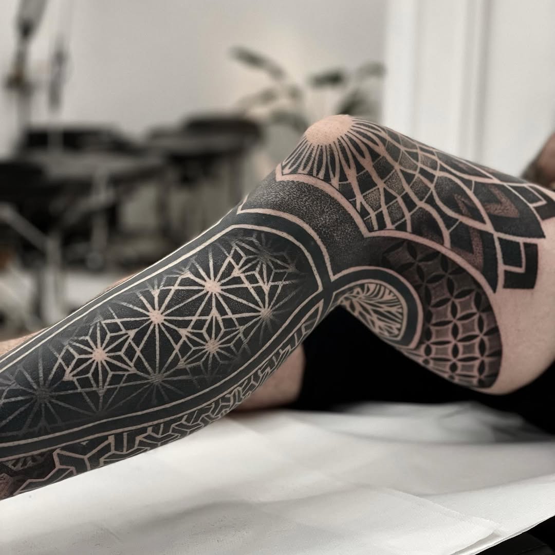 Geometric full-sleeve tattoo with mandalas, intricate dotwork stippling, and ornamental symmetry patterns in black ink.