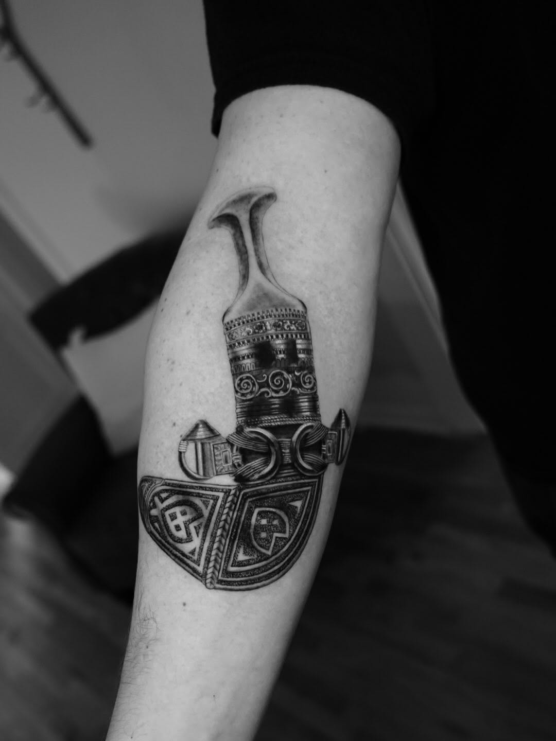 Ornamental brush or paddle with decorative geometric patterns and symmetrical tribal-inspired designs on the forearm.
