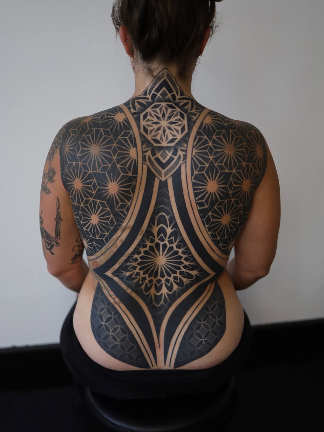 Large-scale mandala and geometric floral pattern covering the back in black and gold symmetrical design.