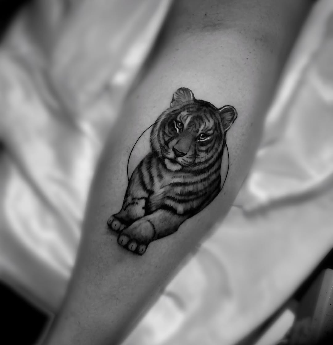 Black and grey realistic tiger head with detailed facial features and stripes on inner arm, looking upward.