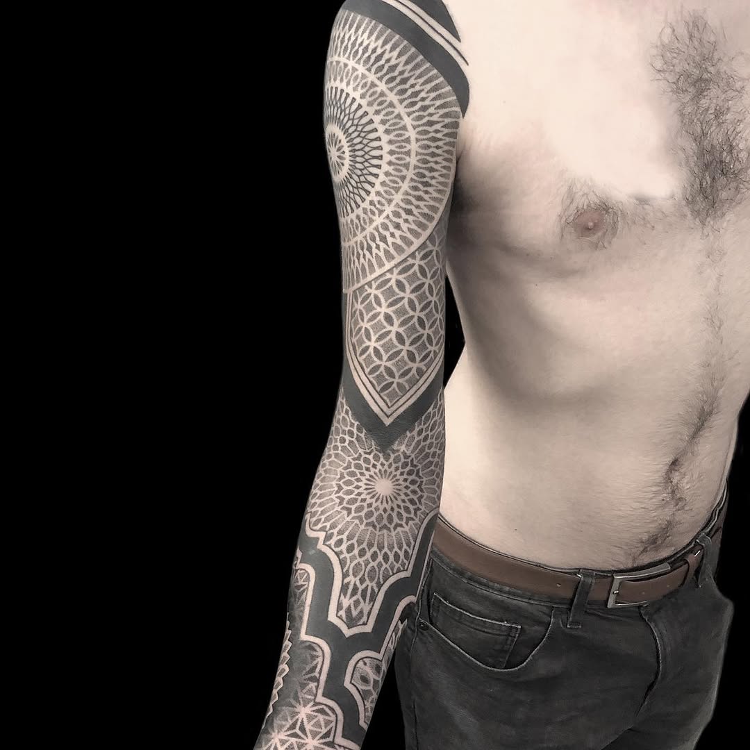 Full sleeve geometric mandala and ornamental dotwork tattoo in black and grey covering the entire left arm.