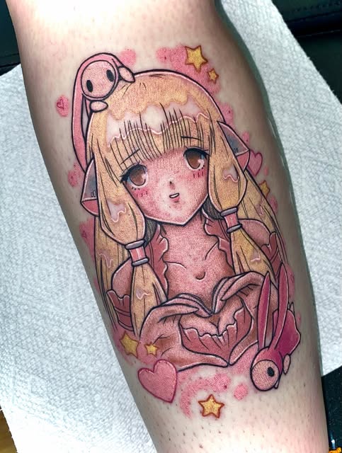 Anime girl character with long blonde hair and large eyes tattooed on forearm, surrounded by pink hearts, stars, and decorative elements in warm tones.