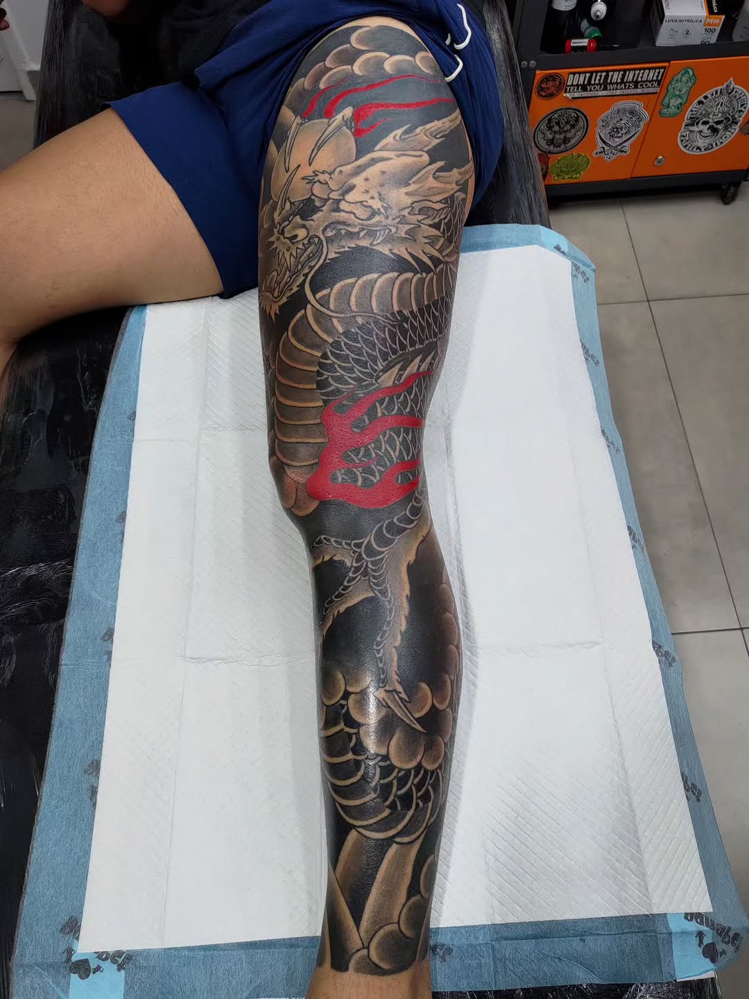 Full leg sleeve featuring a dragon with red accents, scales, and flowing Japanese-inspired design elements on the thigh and calf.